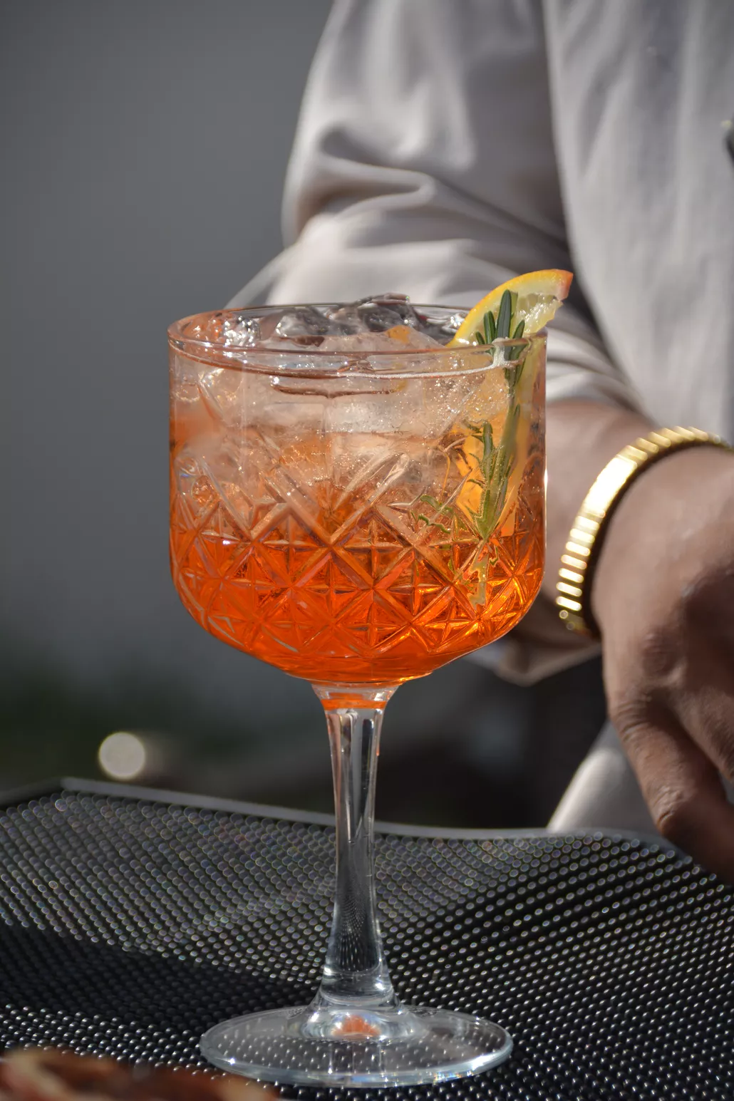 Coctel Spritz naranja en copa labrada con romero y cítrico