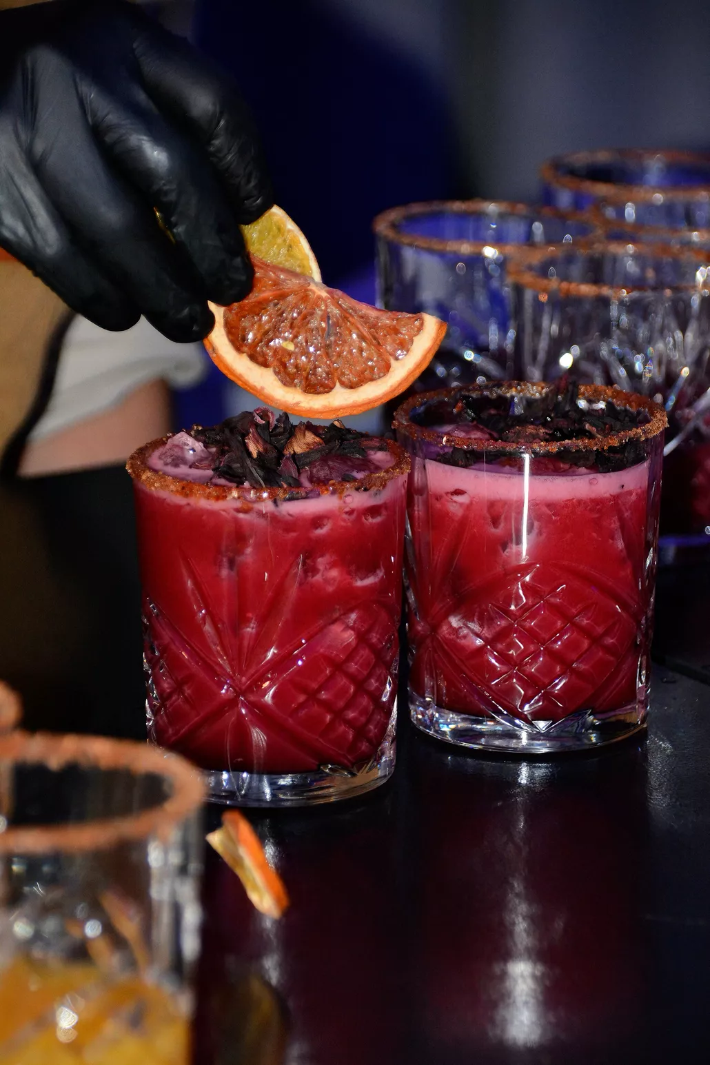 Dos cocteles de jamaica con escarchado de chile y naranja deshidratada