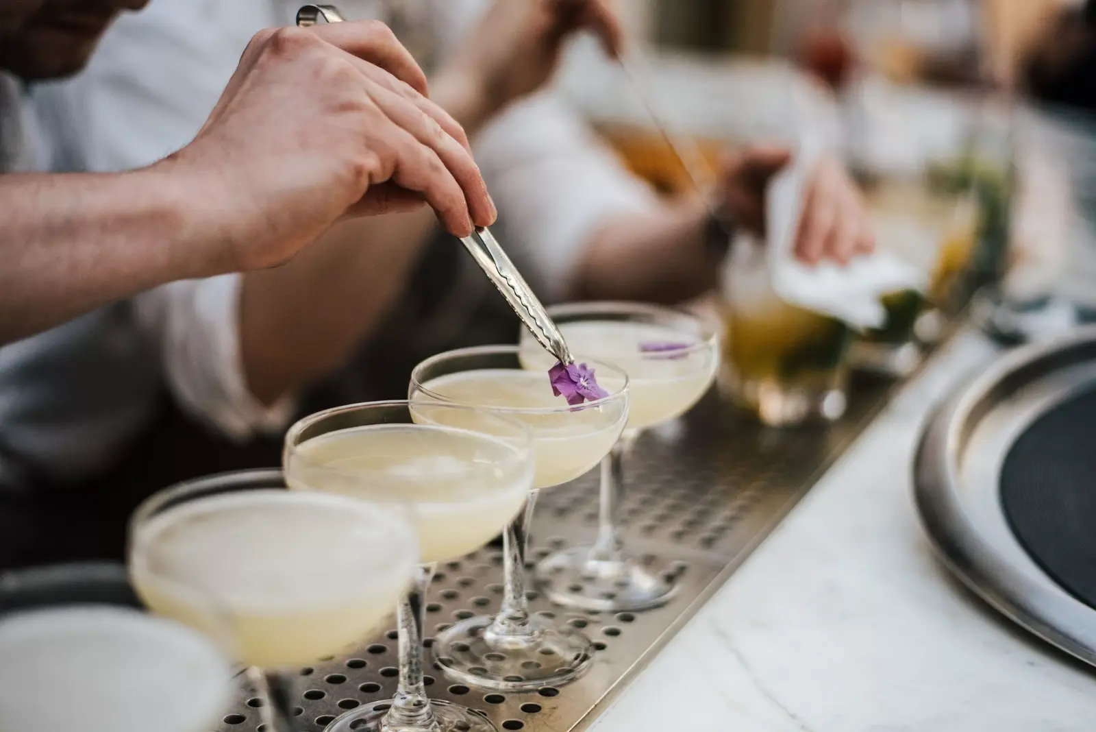Bartender de Kokteli terminando cocteles daiquirí con flor comestible morada