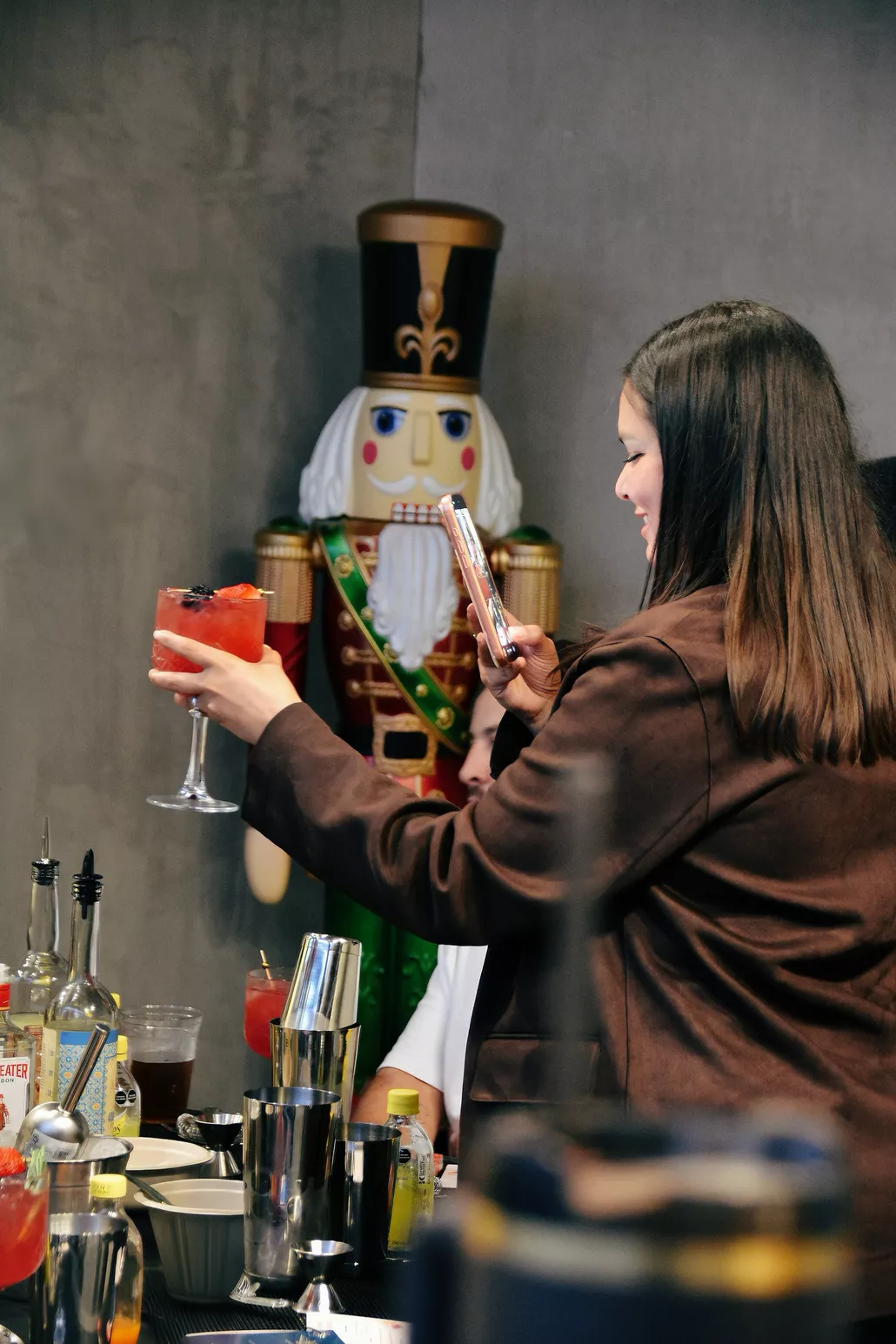 Invitada fotografiando su coctel en evento con decoración navideña